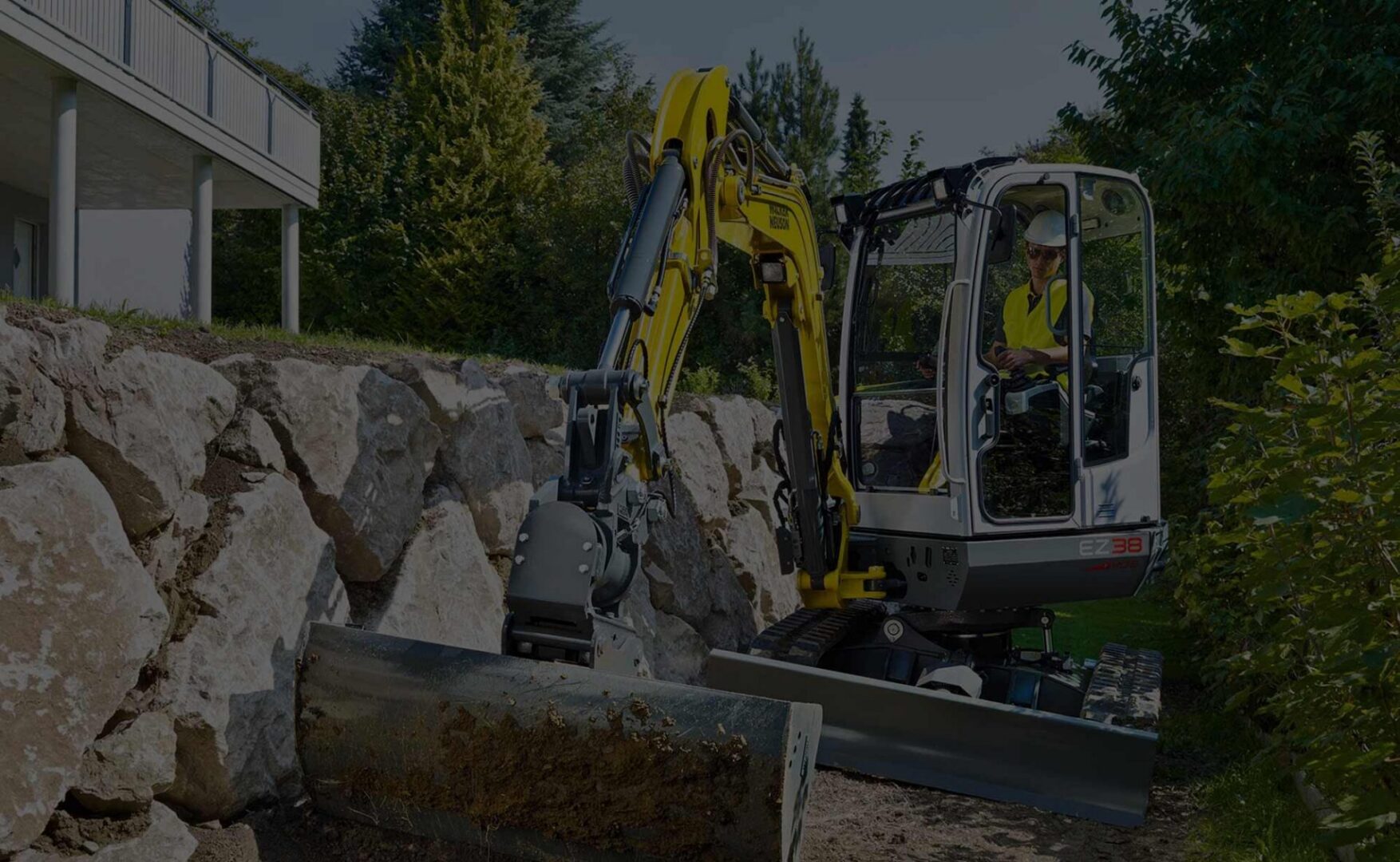 Excavator working near stone wall outdoors
